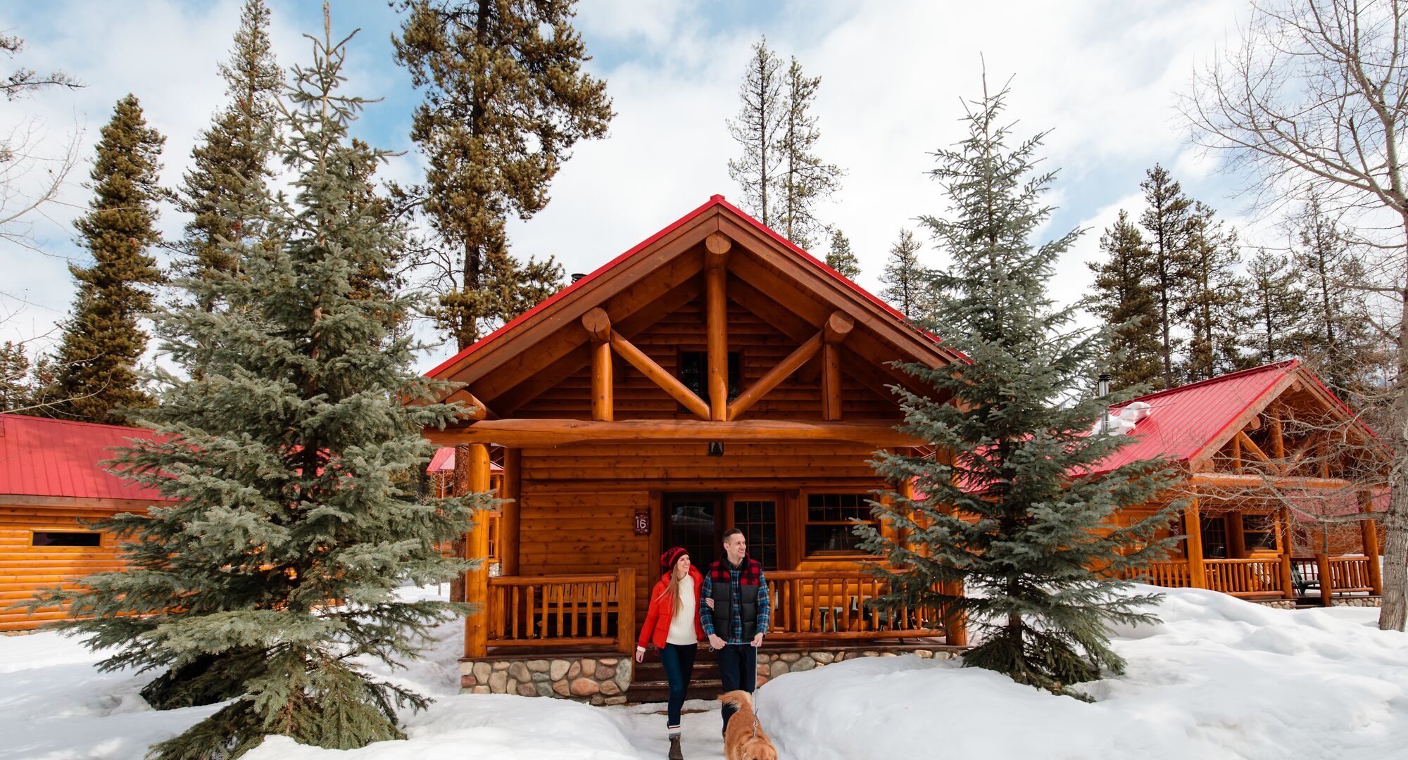 A couple leaves a snowy cabin in the winter at Baker Creek in Banff National Park.